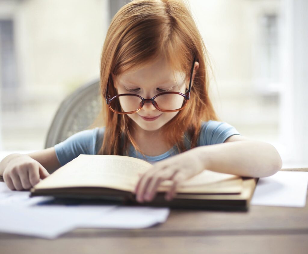 girl in blue long sleeve shirt reading book