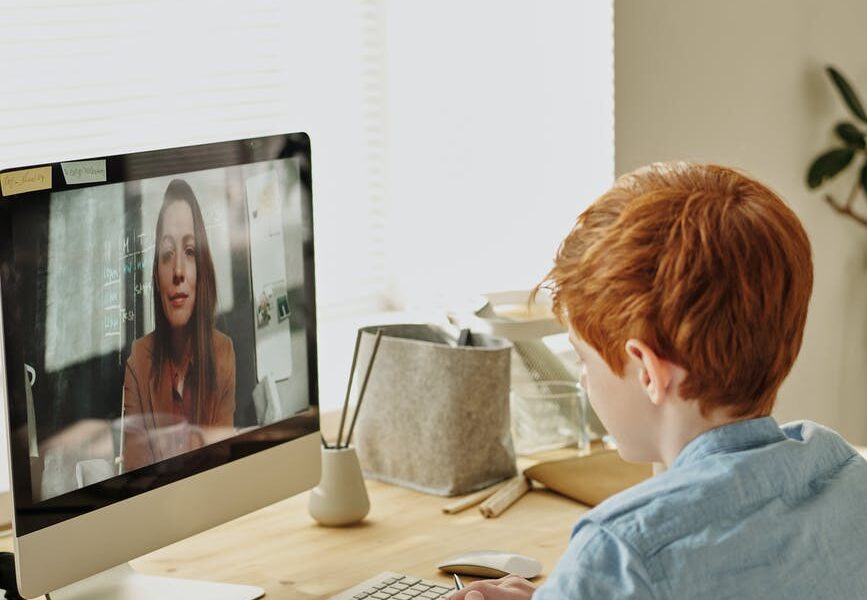 boy in blue dress shirt sitting in front of silver imac